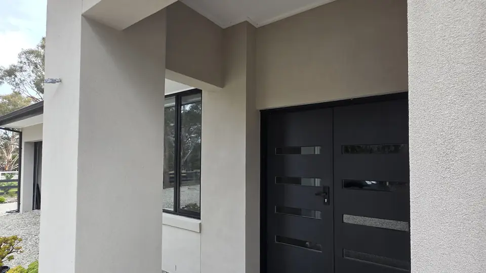 Freshly rendered pillar and entry walls framing a double front door